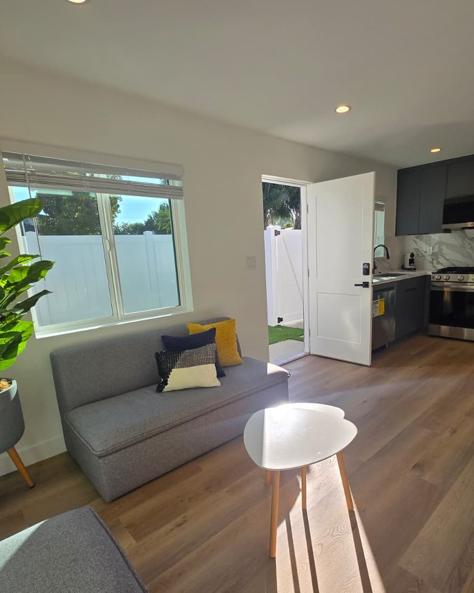 Living room of a KRN-built ADU: sofa, plant and kitchen in morning light